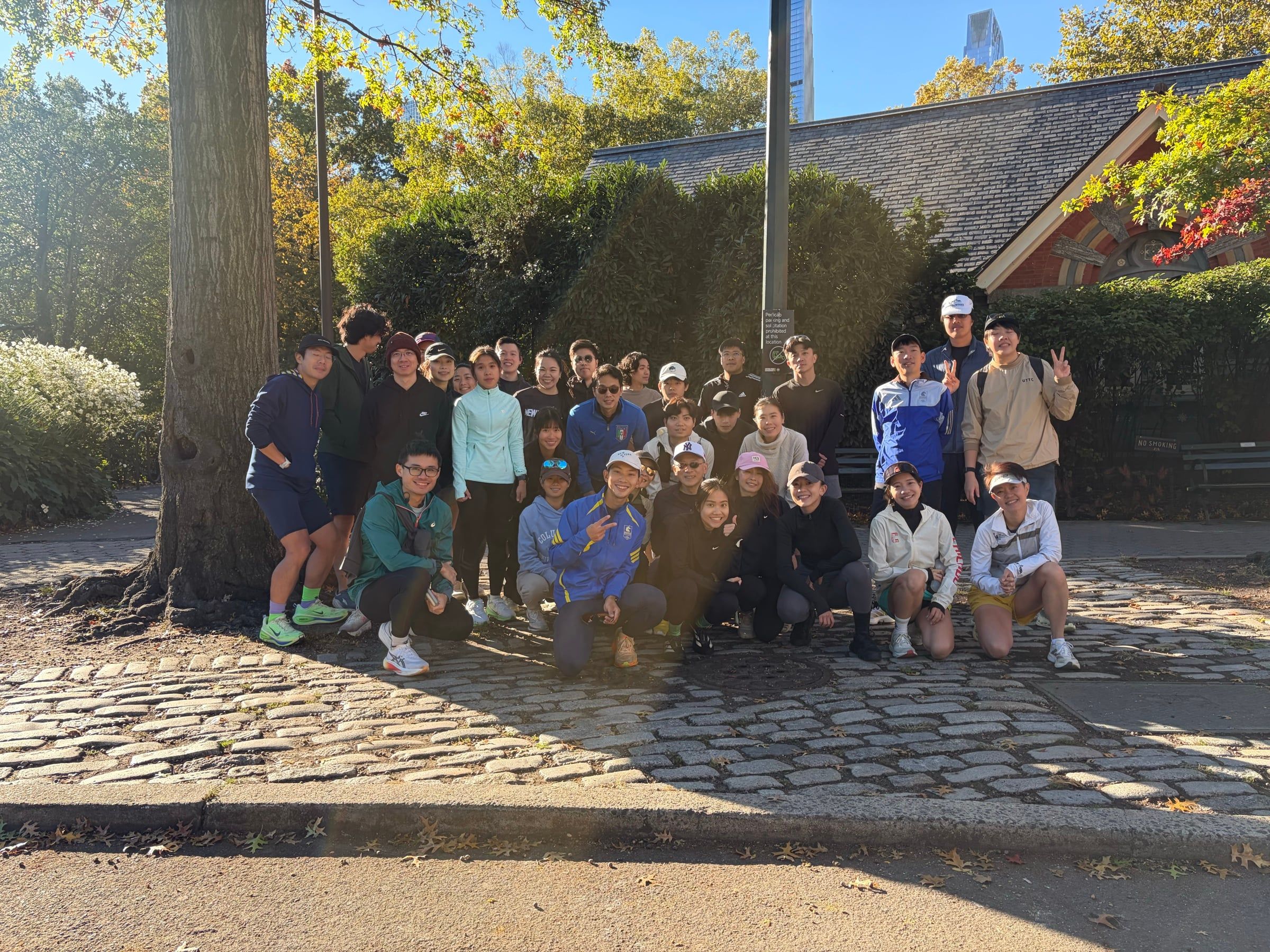 Wide group photo of the crew by Tavern on the Green under autumn trees